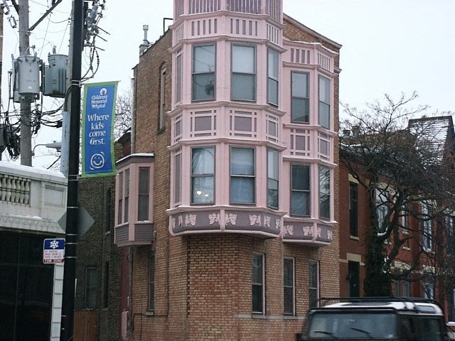 a pink building on the side of a street