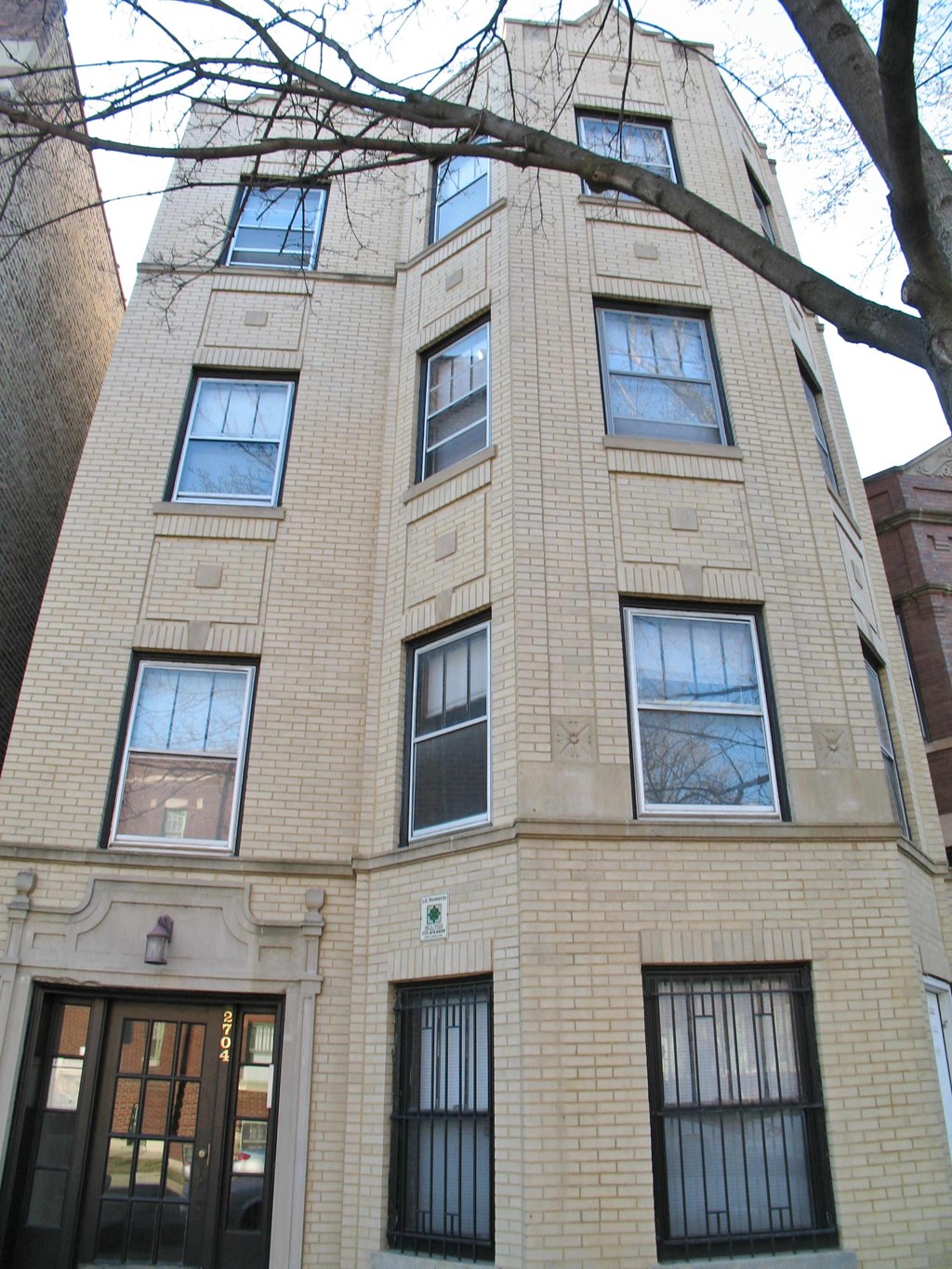 a tall brick building with many windows and a tree