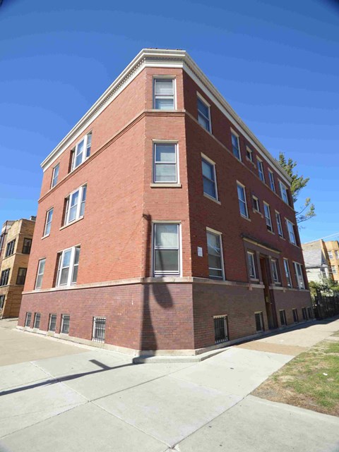 a tall brick building with a sidewalk in front of it