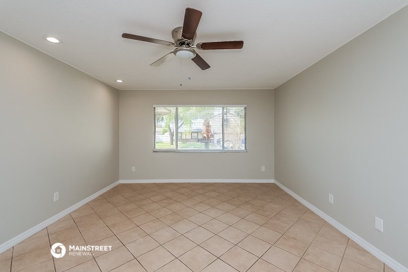 an empty living room with a ceiling fan and a window
