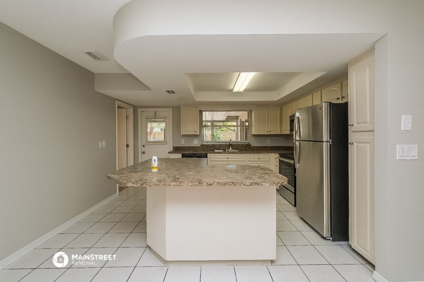 a kitchen with a large island and a stainless steel refrigerator