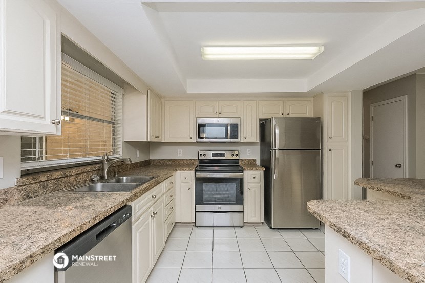 a kitchen with white cabinets and granite counter tops and stainless steel appliances
