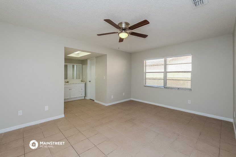 an empty living room with a ceiling fan and a bathroom