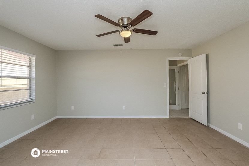 the spacious living room with ceiling fan and tiled floor