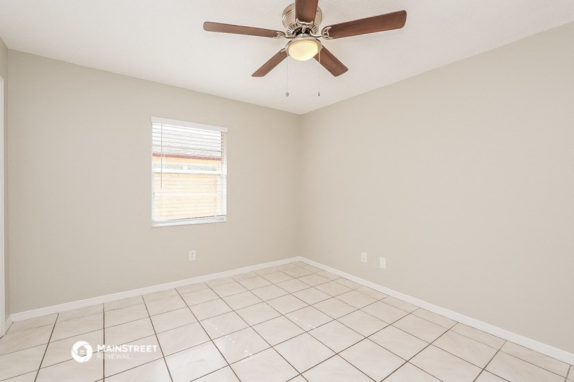 the spacious living room has a ceiling fan and a tiled floor