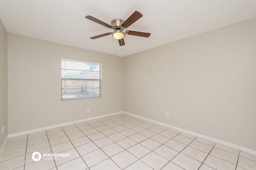 an empty living room with a ceiling fan and a tiled floor