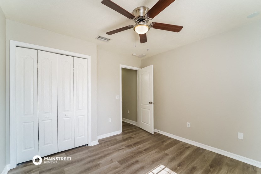 a bedroom with a ceiling fan and a closet