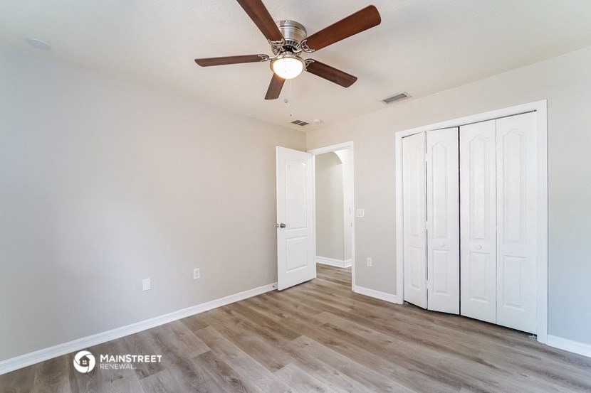a living room with a ceiling fan and a closet