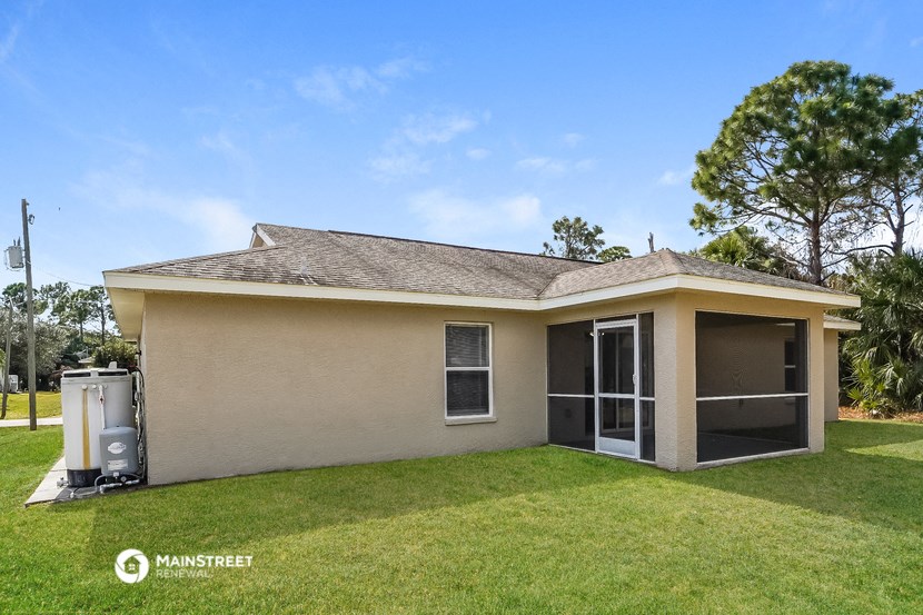 a small tan house with a yard and a water heater