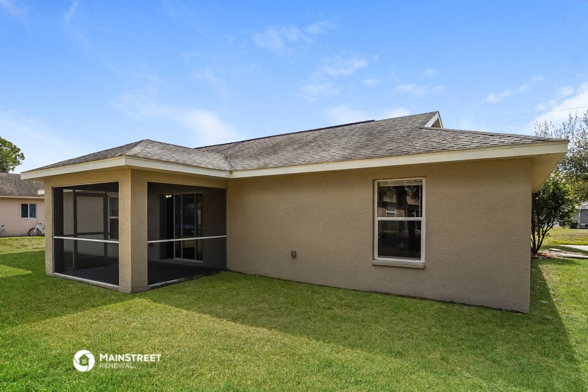 a small tan house with a grassy yard and a patio