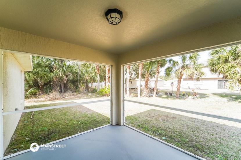 a screened in porch with a view of the yard and palm trees