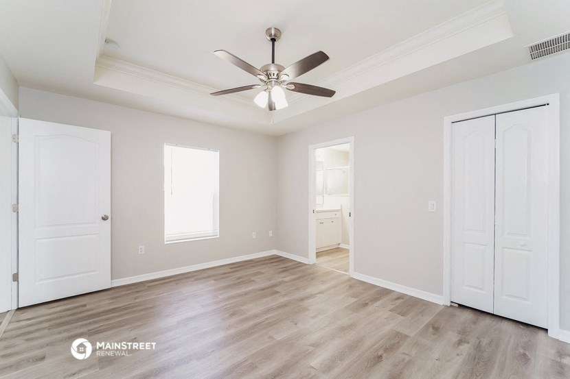 an empty living room with white walls and a ceiling fan