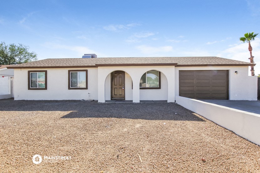 a white house with a brown door and a gravel driveway