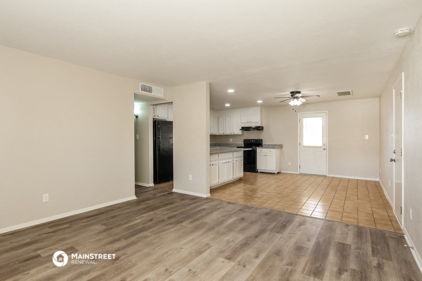 an empty living room and kitchen with wood flooring