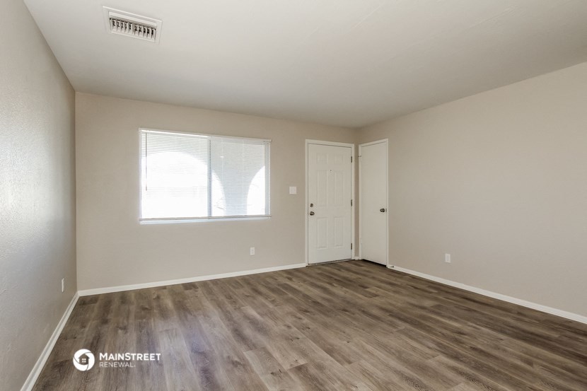 the living room of an empty house with wood flooring