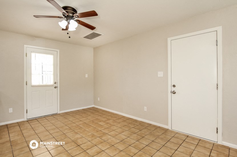 an empty living room with a ceiling fan and a door