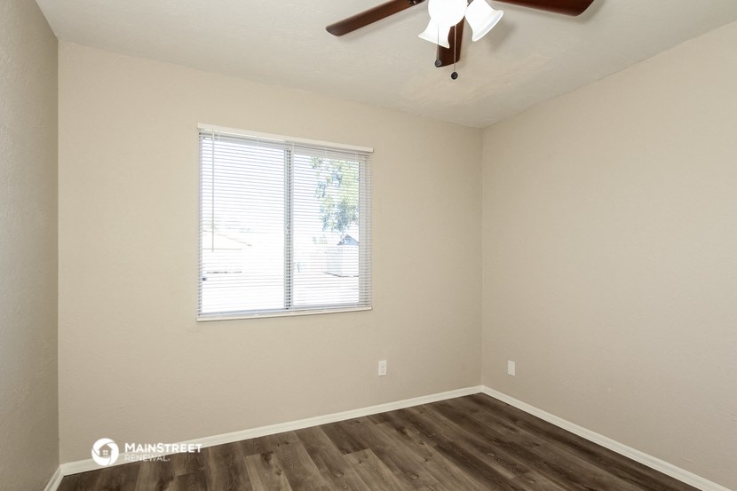 an empty bedroom with a window and a ceiling fan