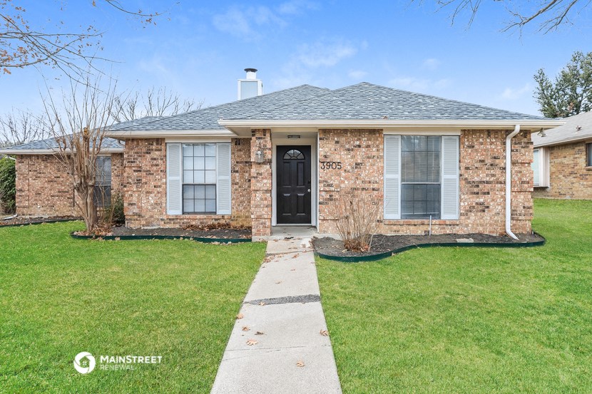 a small brick house with a black door and green grass