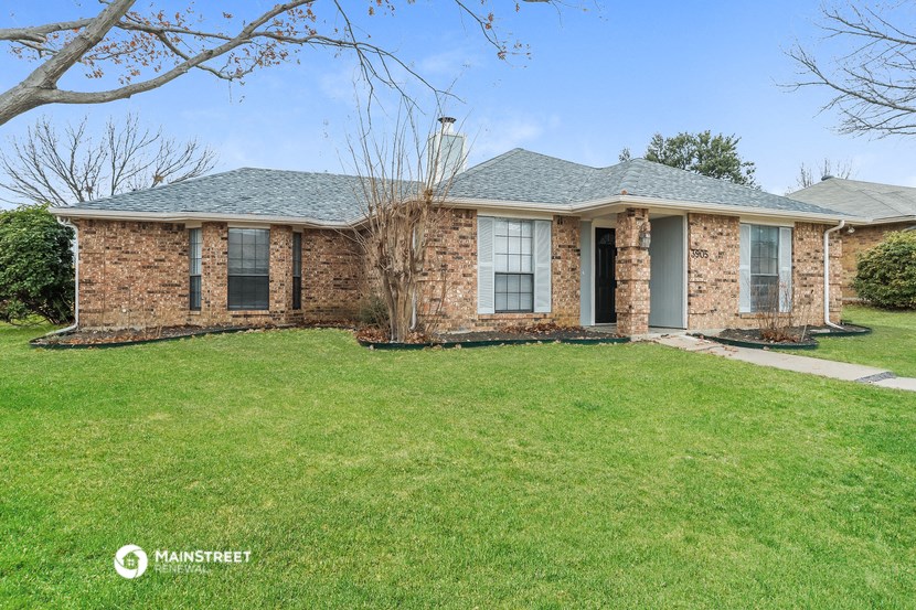 a brick house with a green lawn and a tree