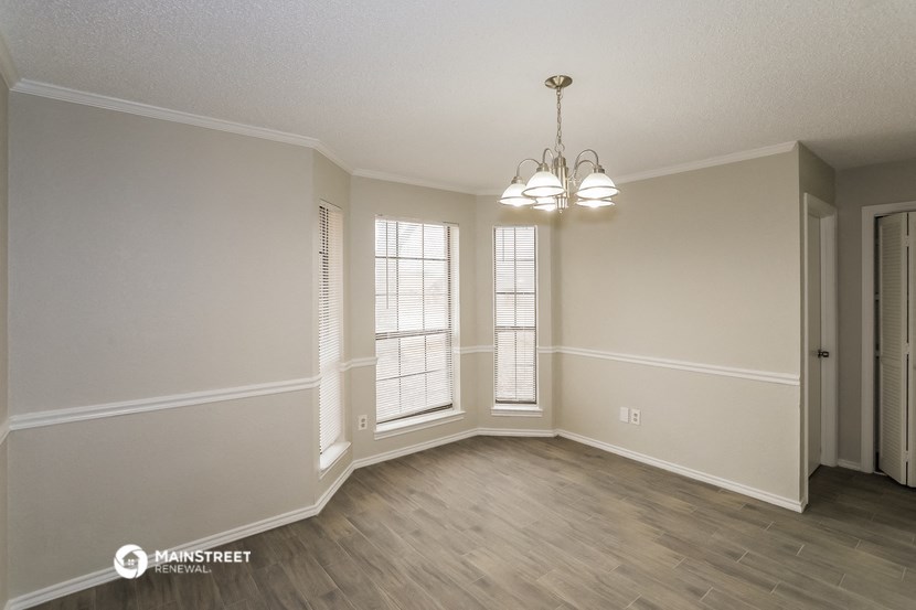 an empty living room with a chandelier and windows