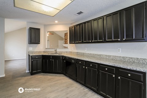 a kitchen with black cabinets and granite counter tops and a sink