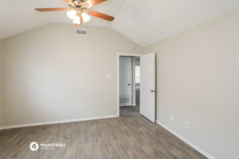 the spacious living room with ceiling fan and wood flooring