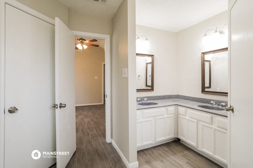 a bathroom with white cabinets and a sink and a mirror