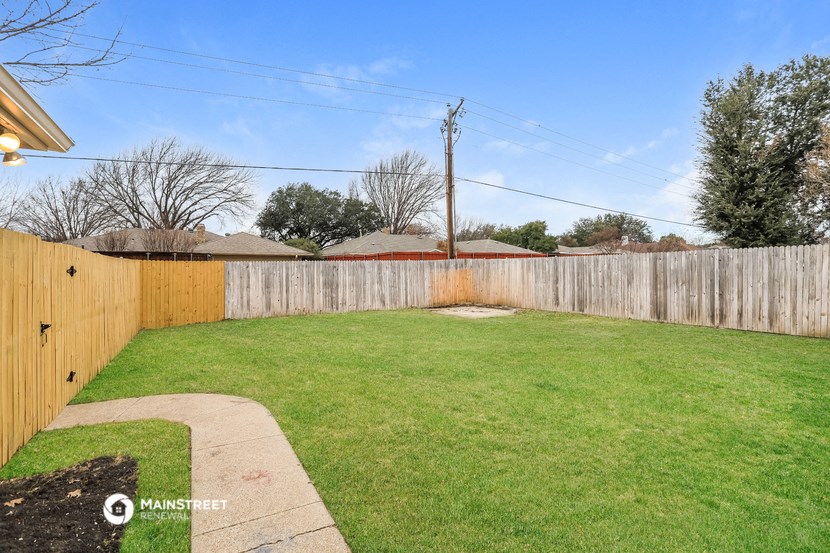 a backyard with a wooden fence and a green lawn