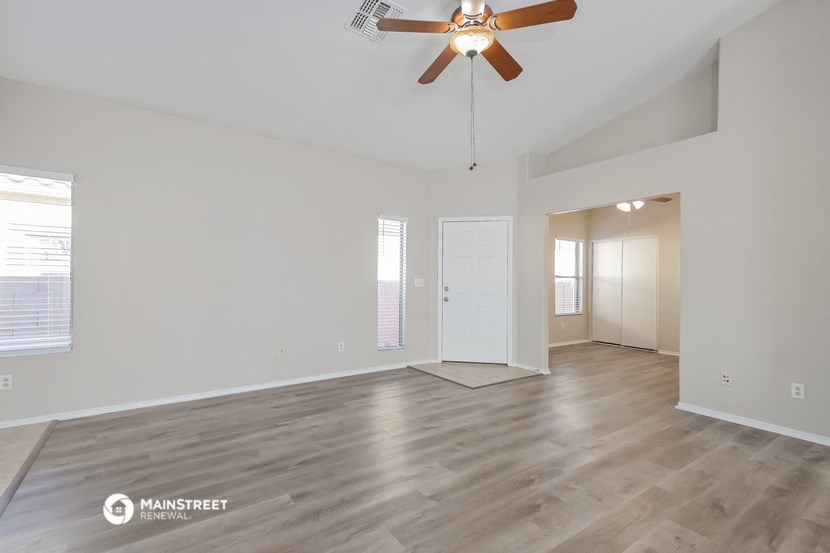 the living room and dining room of an empty house with a ceiling fan