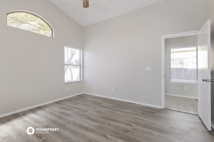 the spacious living room with wood flooring and white walls