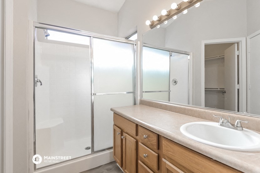 a bathroom with a sink and a shower and a mirror
