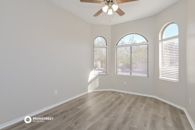 the spacious living room with hardwood flooring and a ceiling fan