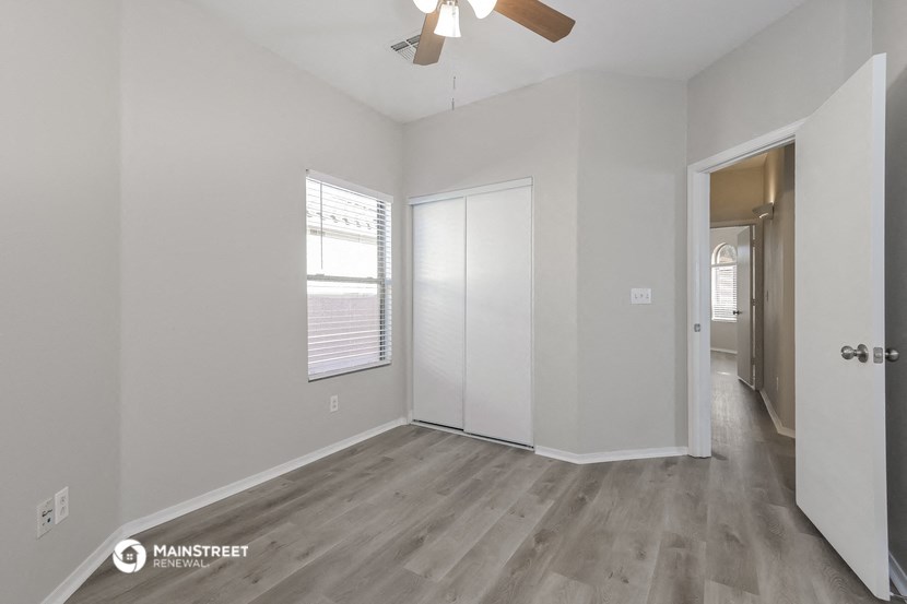 the living room of an empty house with white walls and a ceiling fan