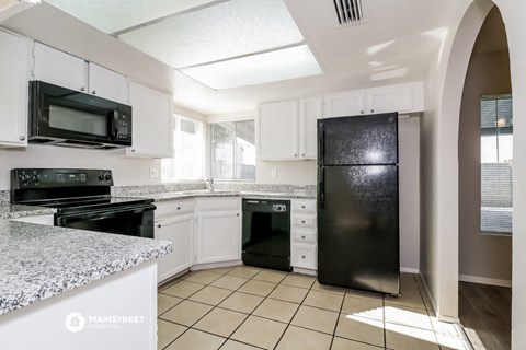 a kitchen with white cabinets and black appliances