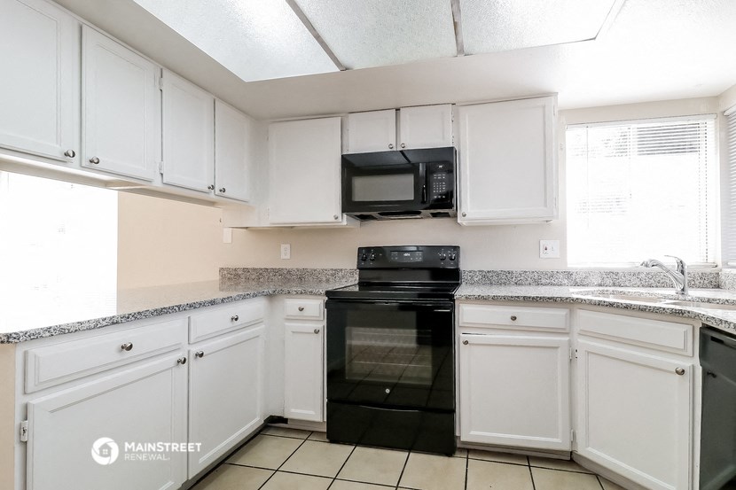 a kitchen with white cabinets and black appliances