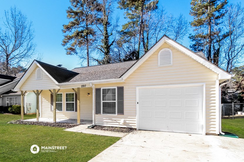 a yellow house with a white garage and a lawn