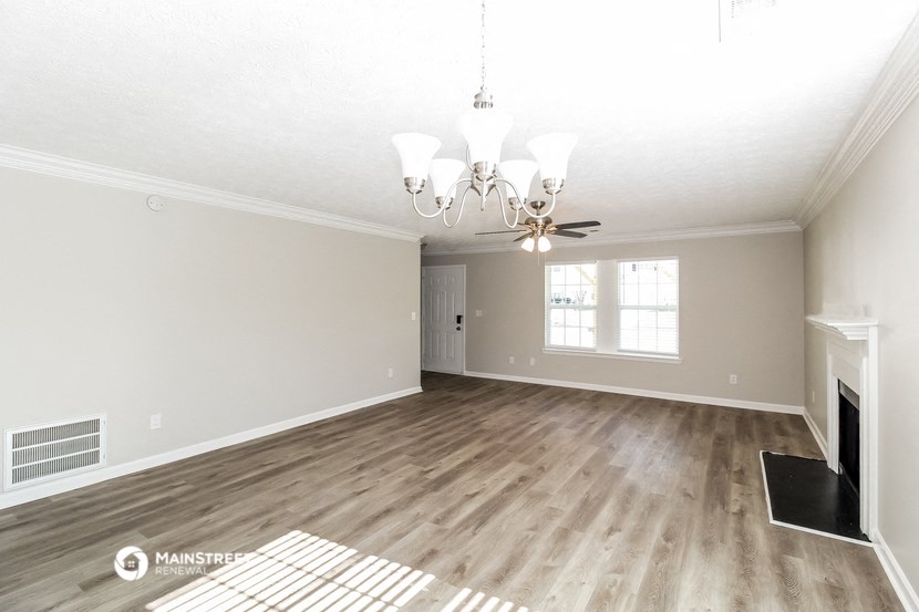 an empty living room with a fireplace and a chandelier
