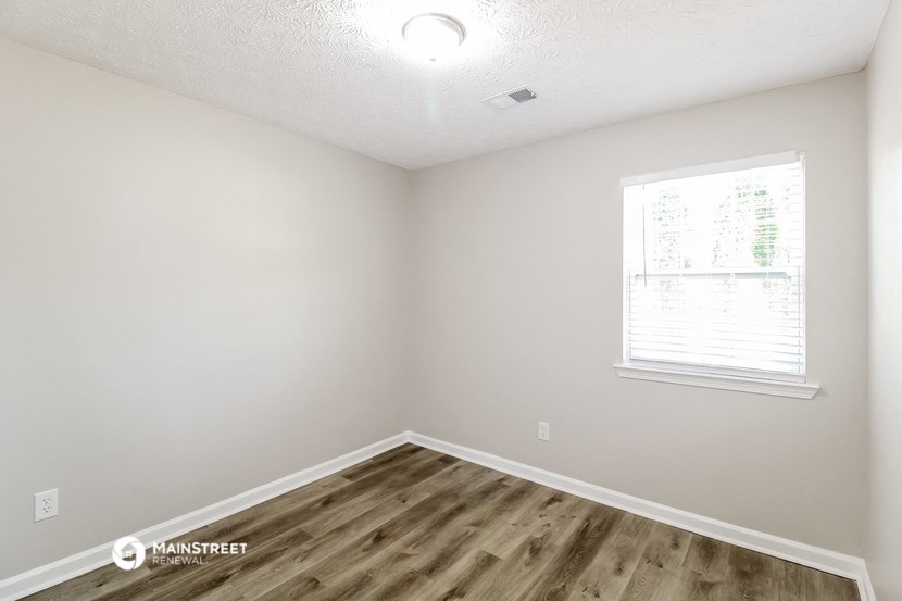 the spacious living room with wood flooring and a window
