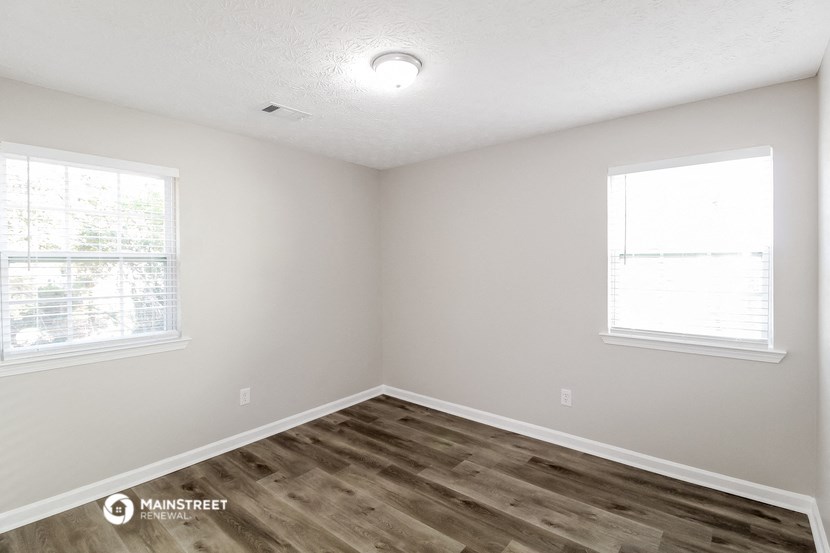 the spacious living room with wood flooring and two windows