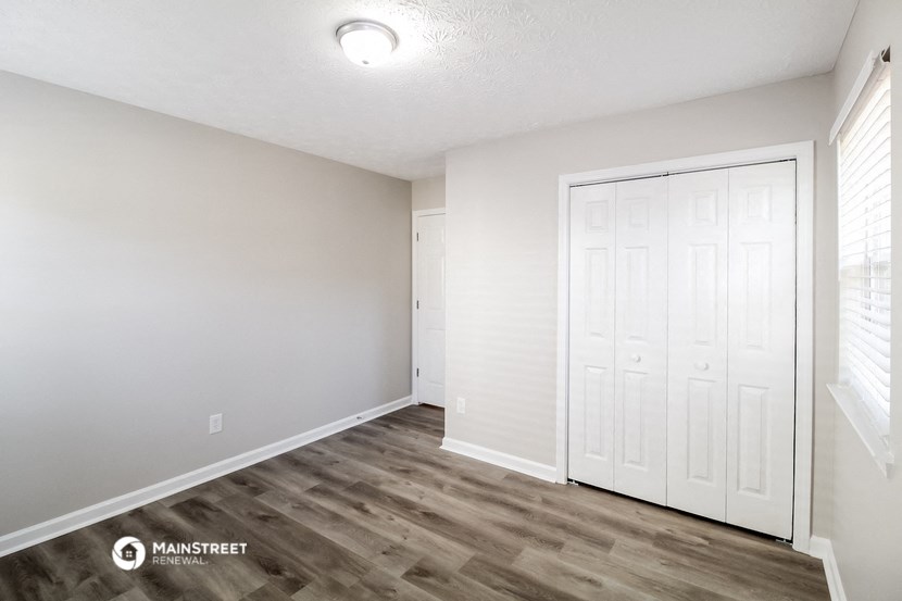 the spacious living room with white walls and wood flooring