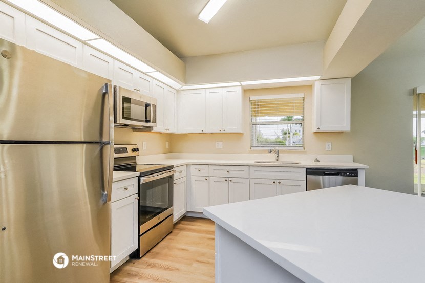 an updated kitchen with white cabinets and stainless steel appliances