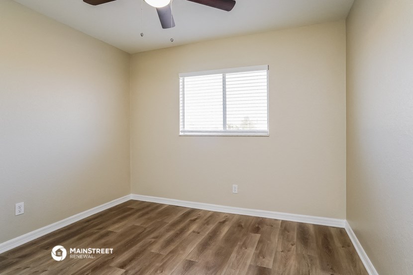 the spacious living room with wood flooring and a window