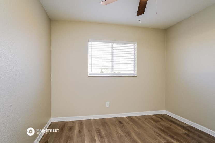 the spacious living room with wood flooring and a window