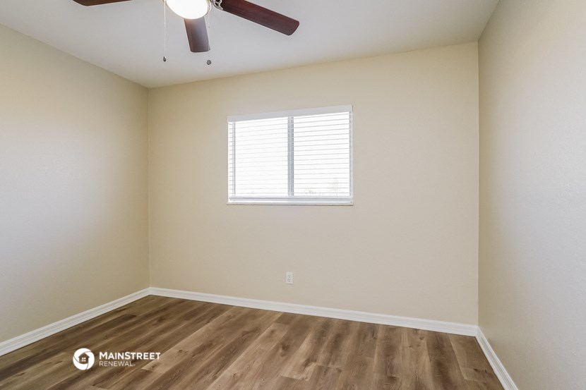 the spacious living room with wood flooring and a ceiling fan