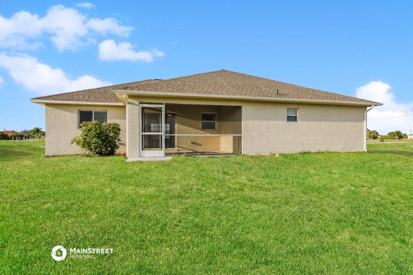 a small tan house with a grass yard and a blue sky