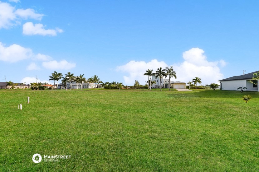 a large field of grass with palm trees in the background