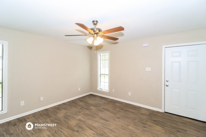 the spacious living room with ceiling fan and wood flooring