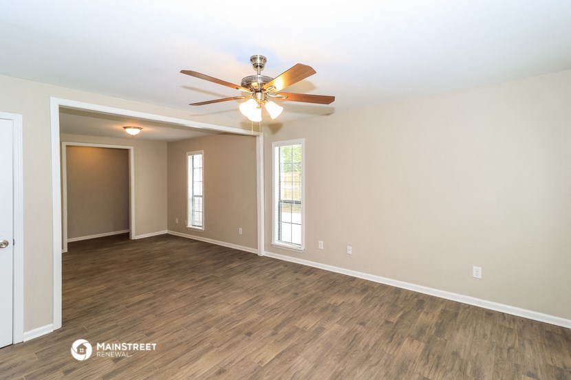 the spacious living room with ceiling fan and wood flooring