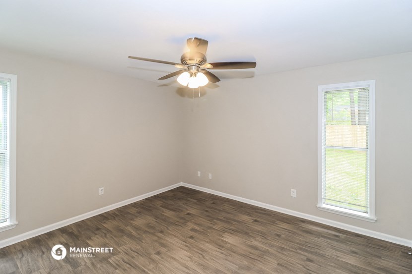 the spacious living room with ceiling fan and wood flooring