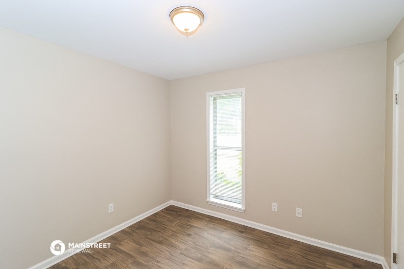 the spacious living room with hardwood flooring and a window